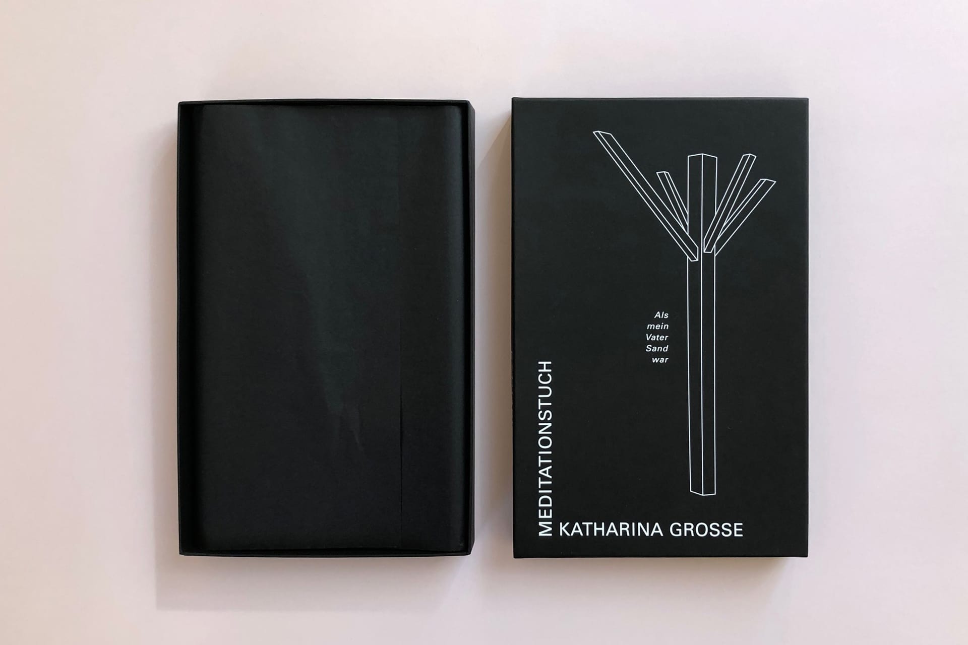 Das Foto zeigt eine schwarze Schachtel, Boden und Deckel mit weißer Schrift.